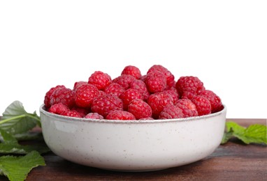 Bowl of fresh ripe raspberries with green leaves on wooden against white background