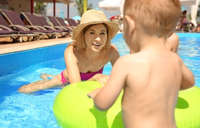 Happy mother with little child in swimming pool outdoors