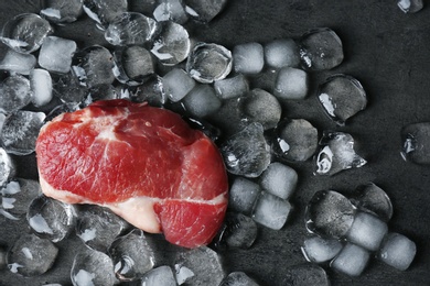 Flat lay composition with raw meat and ice cubes on dark background