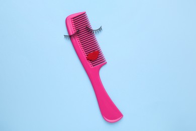 Photo of False eyelashes, red lips and hair comb on light blue background, top view