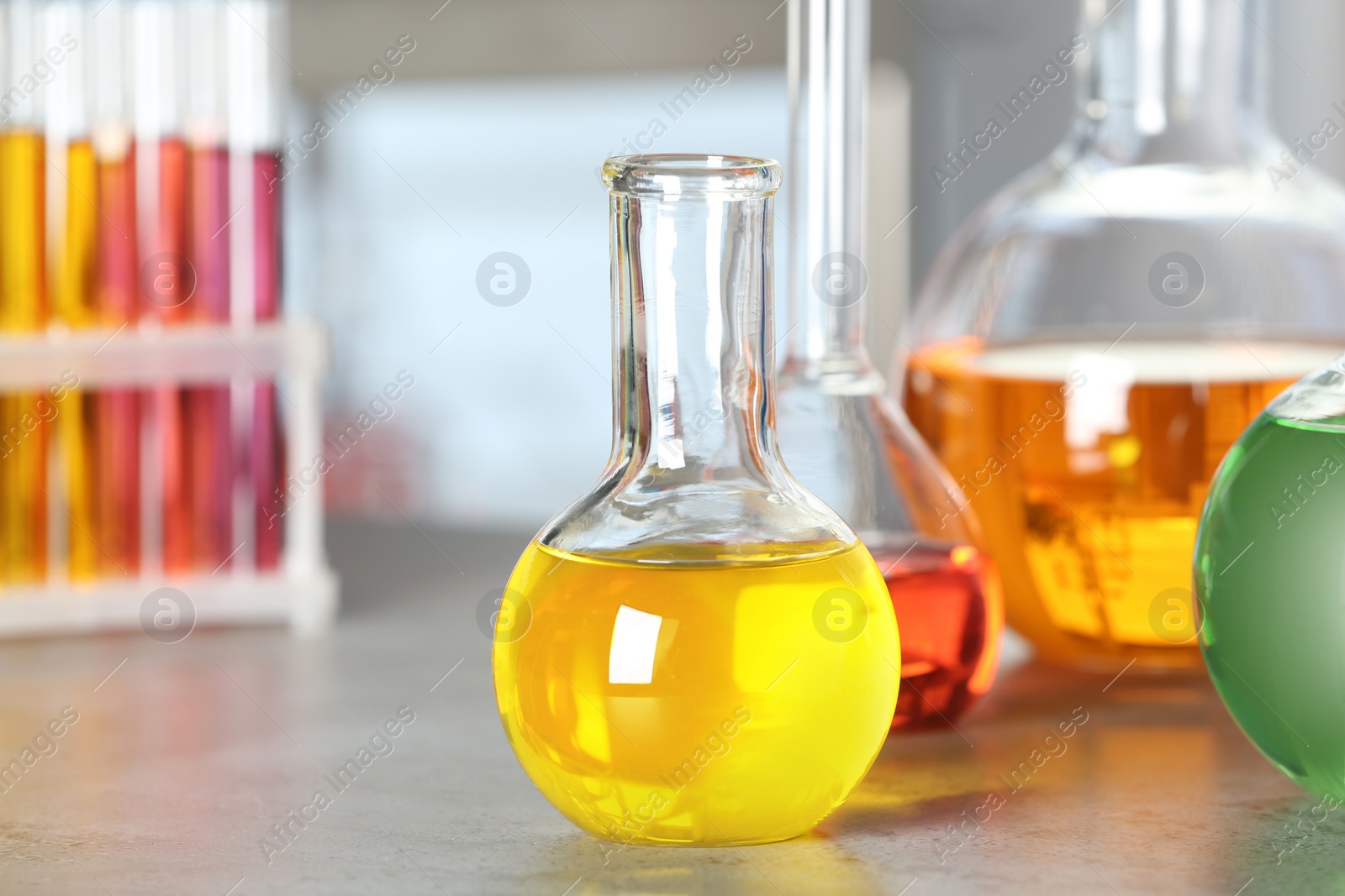 Photo of Florence flask with colorful liquid on grey stone table in laboratory