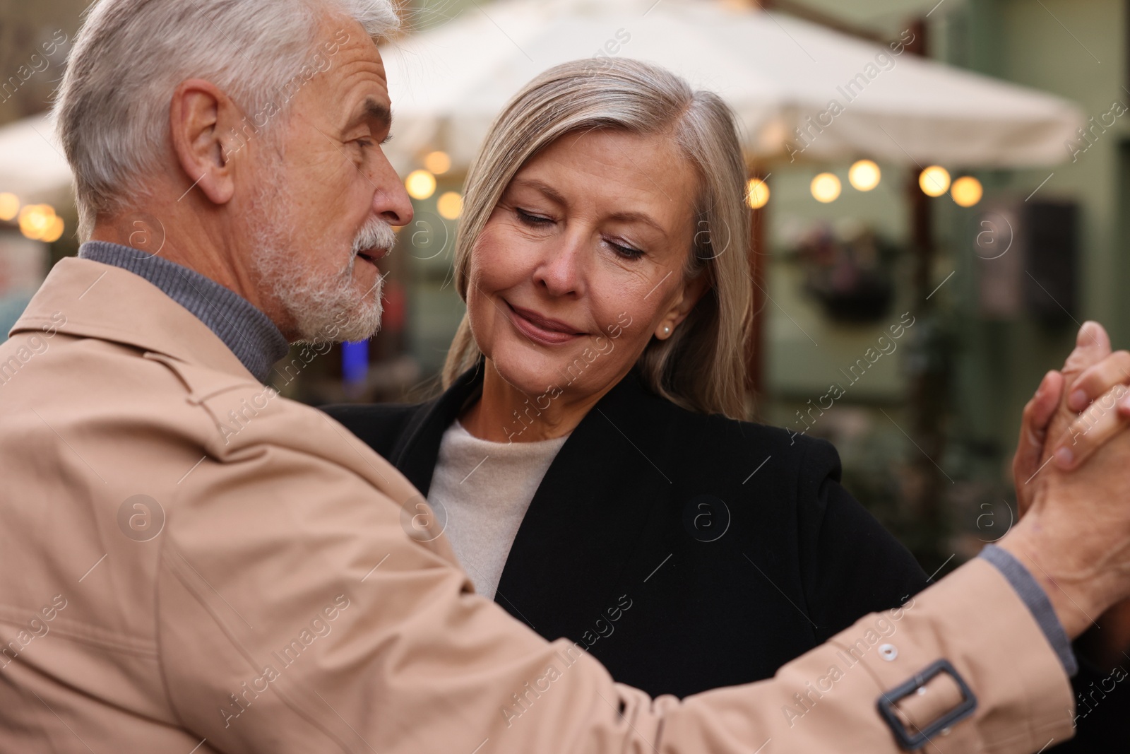 Photo of Affectionate senior couple dancing together on city street