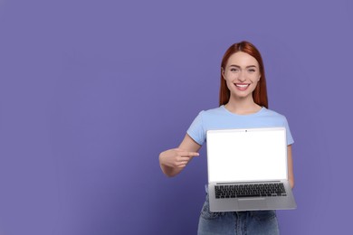 Photo of Smiling young woman showing laptop on lilac background, space for text