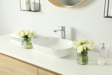 White sink between beautiful roses and toiletries in bathroom