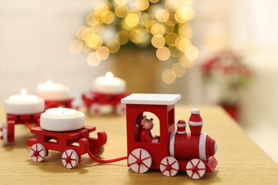 Red toy train as Christmas candle holder on wooden table in room, closeup