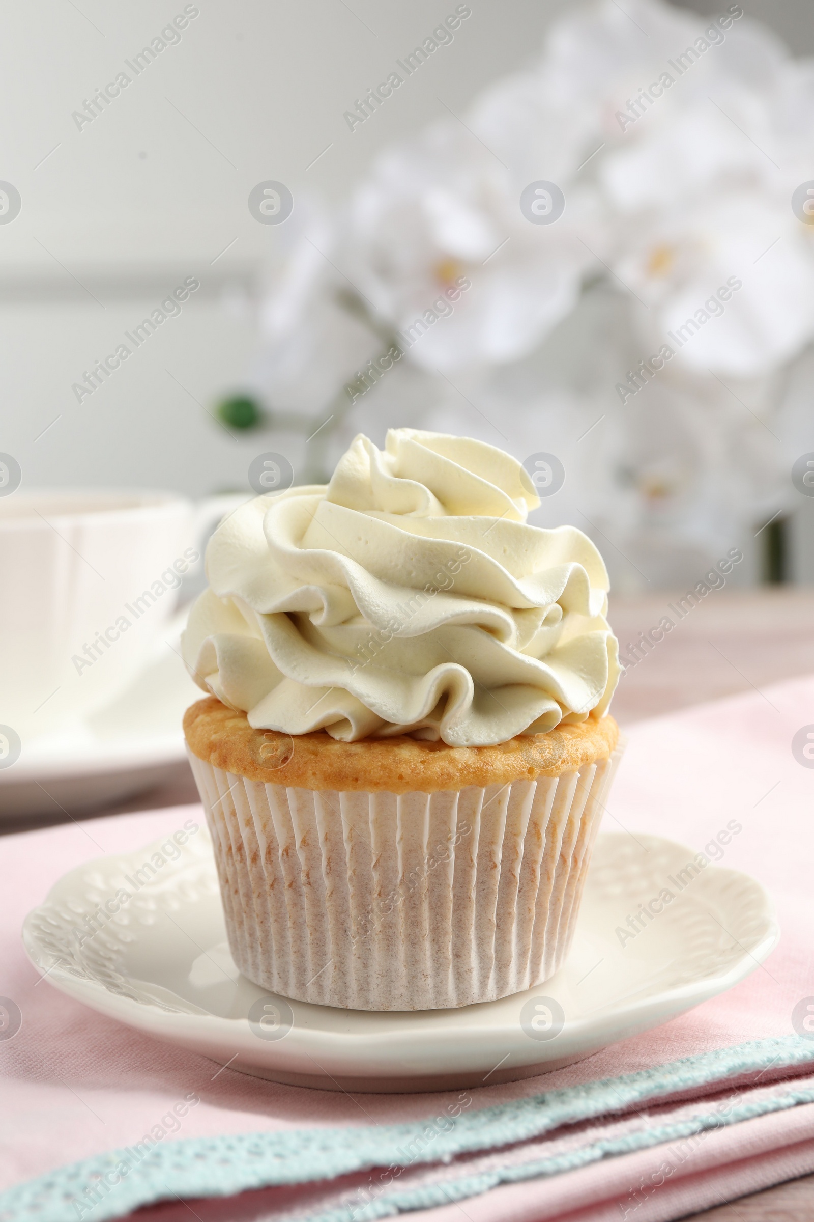 Photo of Tasty cupcake with vanilla cream on table, closeup