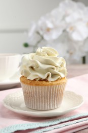 Tasty cupcake with vanilla cream on table, closeup