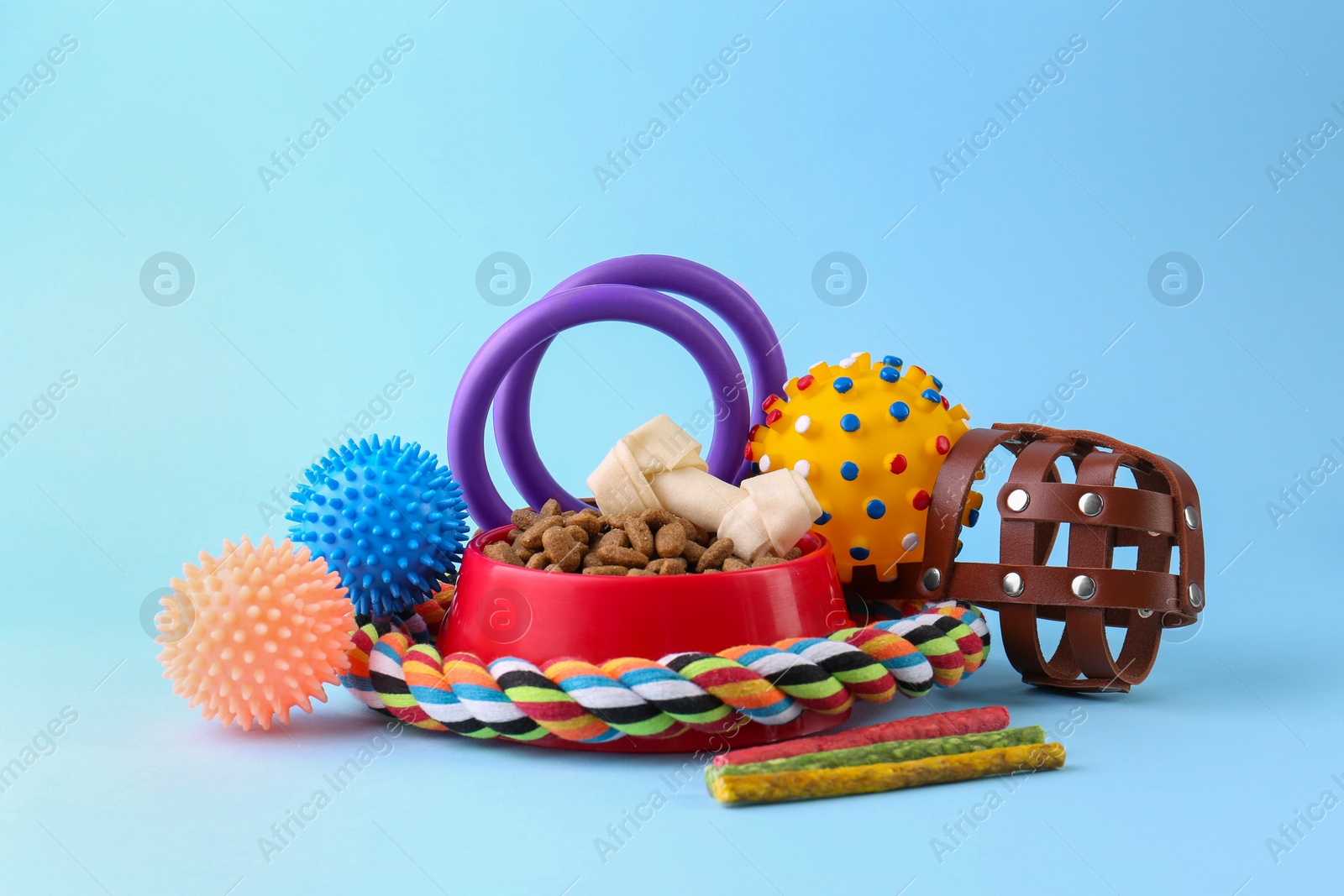 Photo of Dry pet food, toys and other goods on light blue background. Shop items