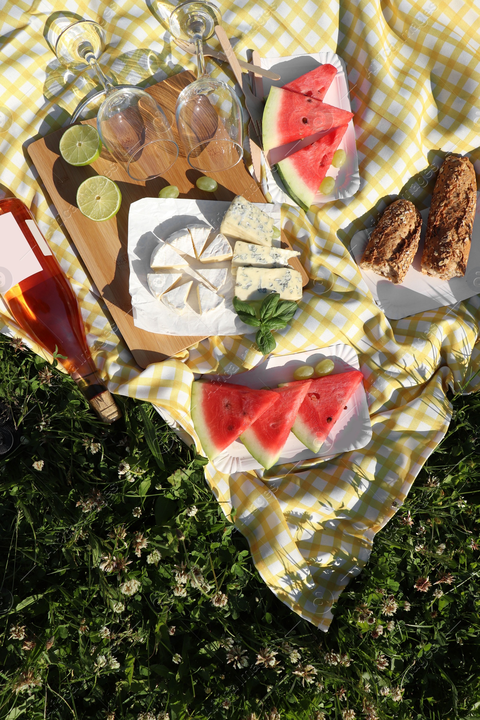 Photo of Picnic blanket with delicious food and wine on green grass outdoors, top view