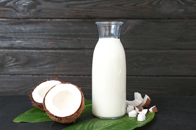 Bottle of coconut milk with fresh nuts on wooden table