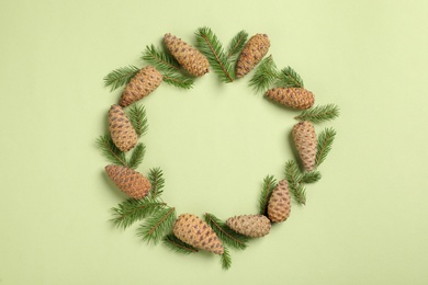 Frame of pinecones and fir branches on green background, flat lay. Space for text