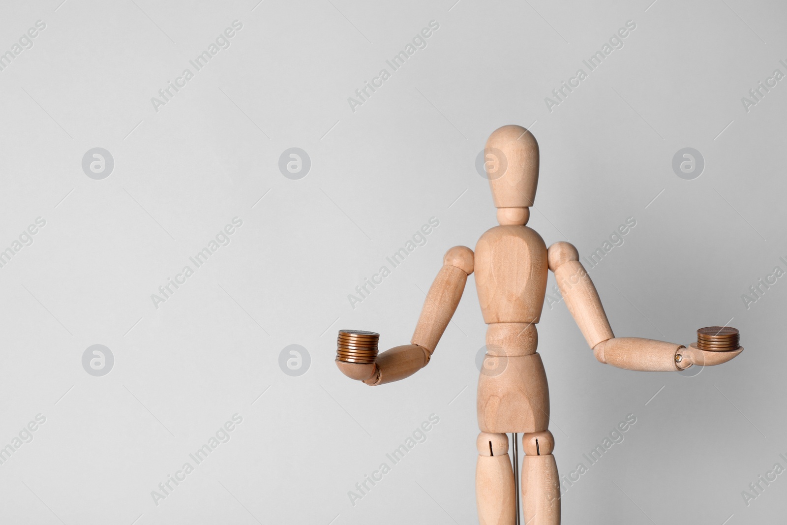 Photo of Wooden human figure balancing stacks of coins on light background, space for text. Harmony concept
