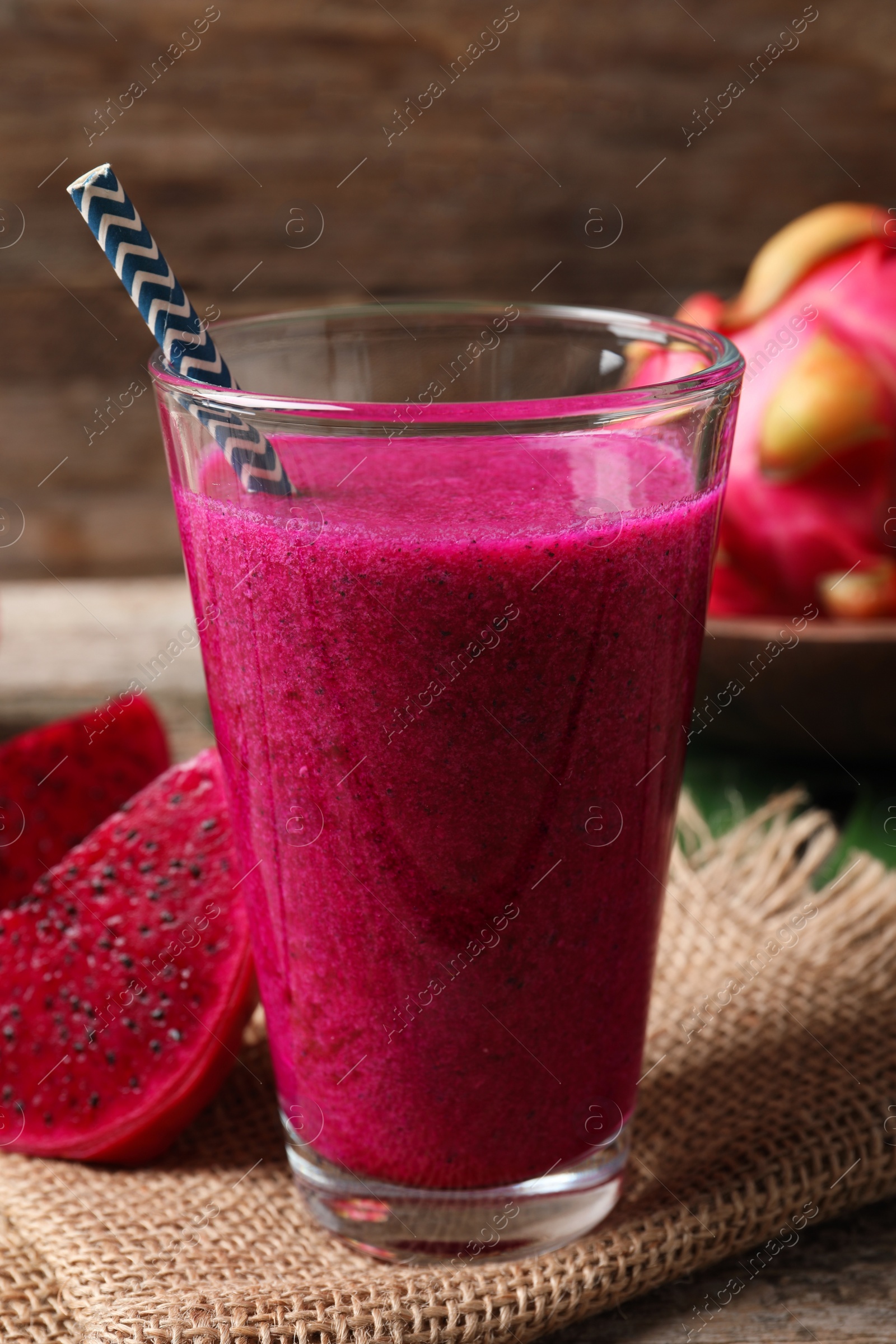 Photo of Glass of tasty pitahaya smoothie and fresh fruits on wooden table