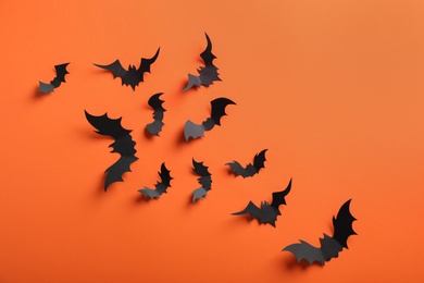 Photo of Paper bats on orange background, flat lay. Halloween decor
