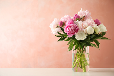 Photo of Beautiful peony bouquet in vase on table against pink background. Space for text