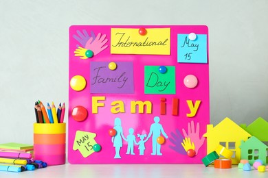 Photo of Magnetic board with text International Family Day and paper cutouts on white table
