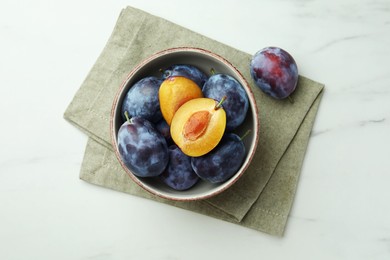 Tasty ripe plums on white marble table, flat lay
