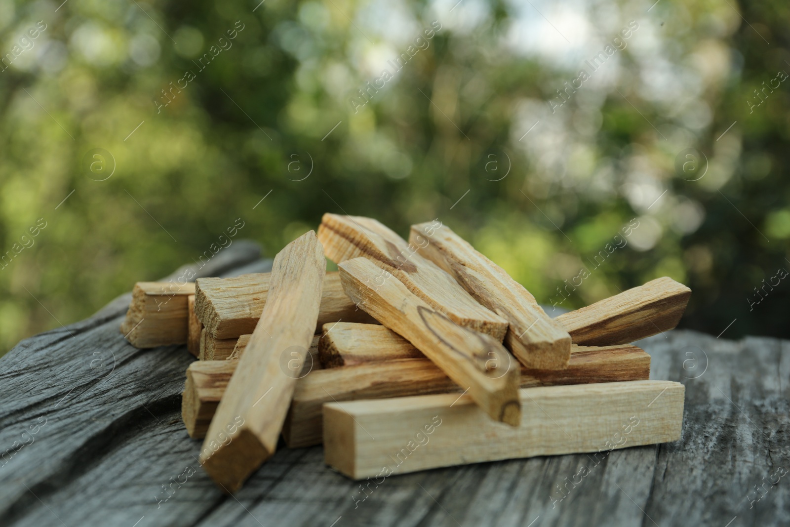 Photo of Palo santo sticks on wooden table outdoors, closeup