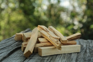 Photo of Palo santo sticks on wooden table outdoors, closeup