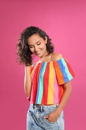 Happy young woman in casual outfit on pink background