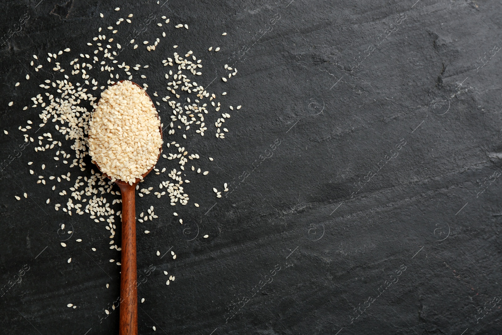 Photo of White sesame seeds on black table, flat lay. Space for text