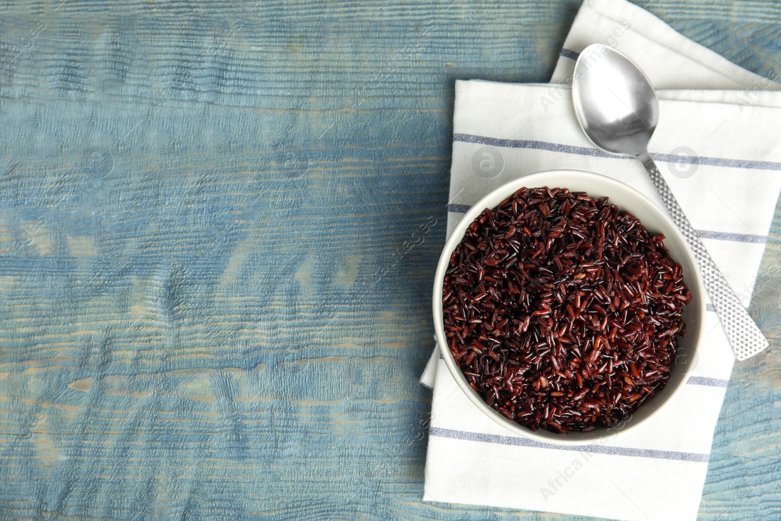 Photo of Flat lay composition with delicious cooked brown rice on color wooden table. Space for text