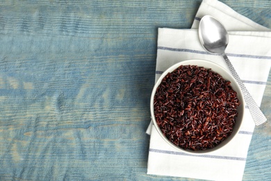 Photo of Flat lay composition with delicious cooked brown rice on color wooden table. Space for text