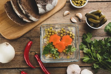 Delicious aspic with meat and ingredients on wooden table, flat lay