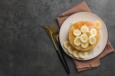 Photo of Tasty pancakes with sliced banana and honey served on gray table, flat lay. Space for text