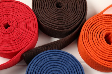 Photo of Colorful karate belts on light background, closeup