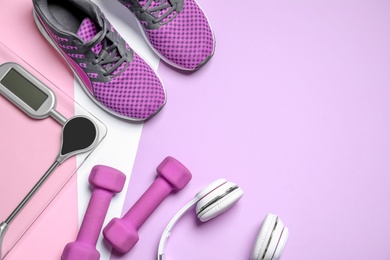 Photo of Headphones, dumbbells, floor scale and shoes on pink background, flat lay. Space for text