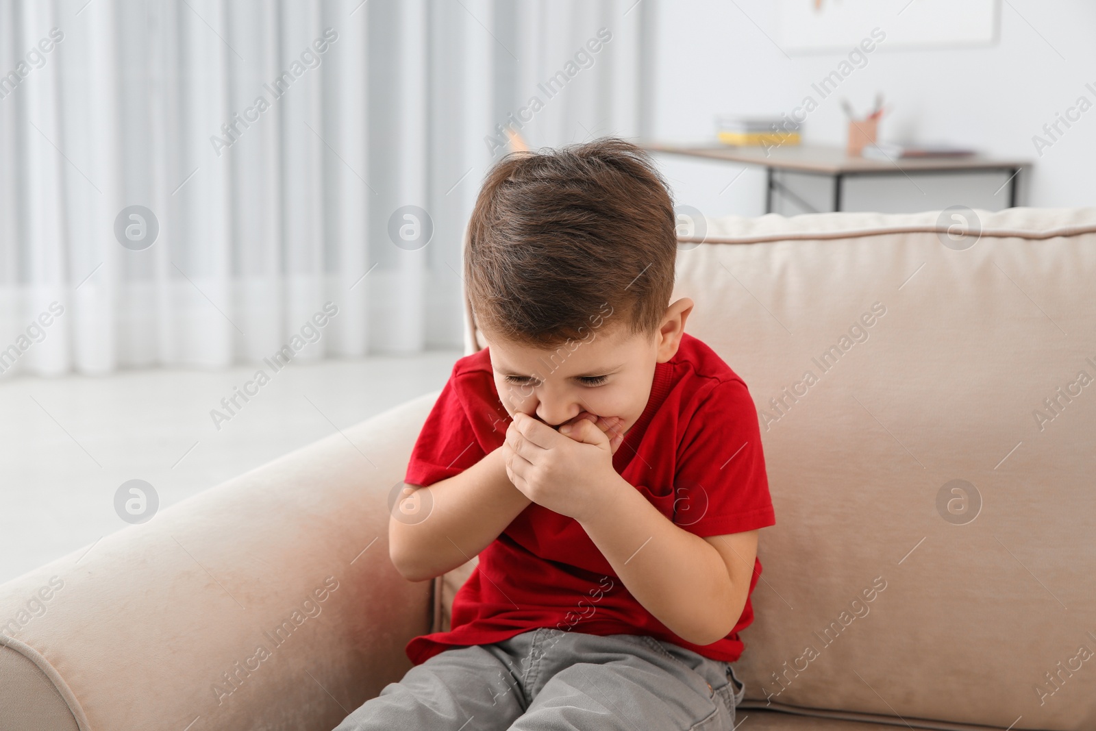 Photo of Little boy suffering from nausea in living room