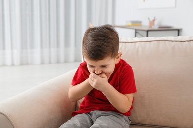 Photo of Little boy suffering from nausea in living room