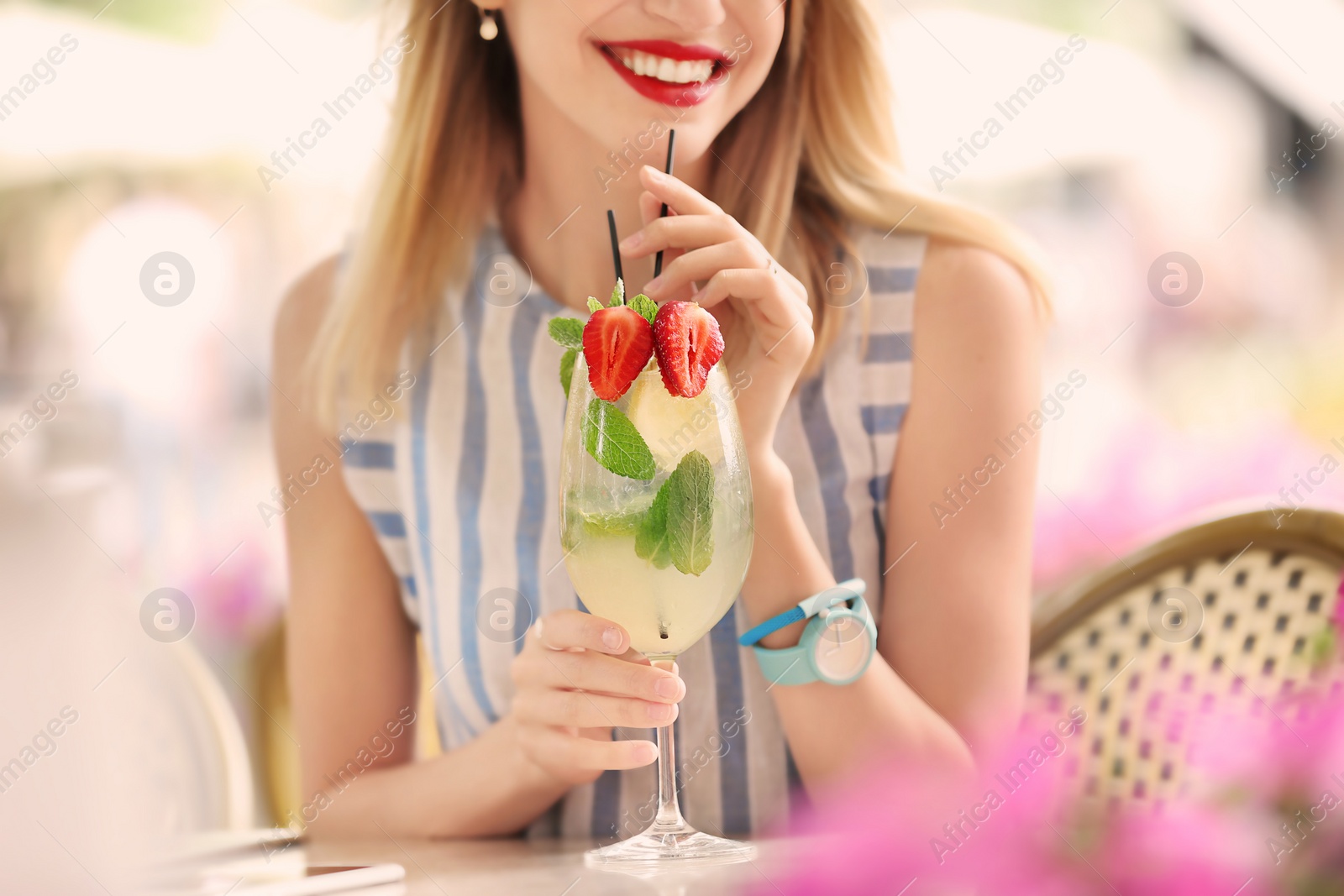 Photo of Young woman with glass of tasty lemonade in open-air cafe