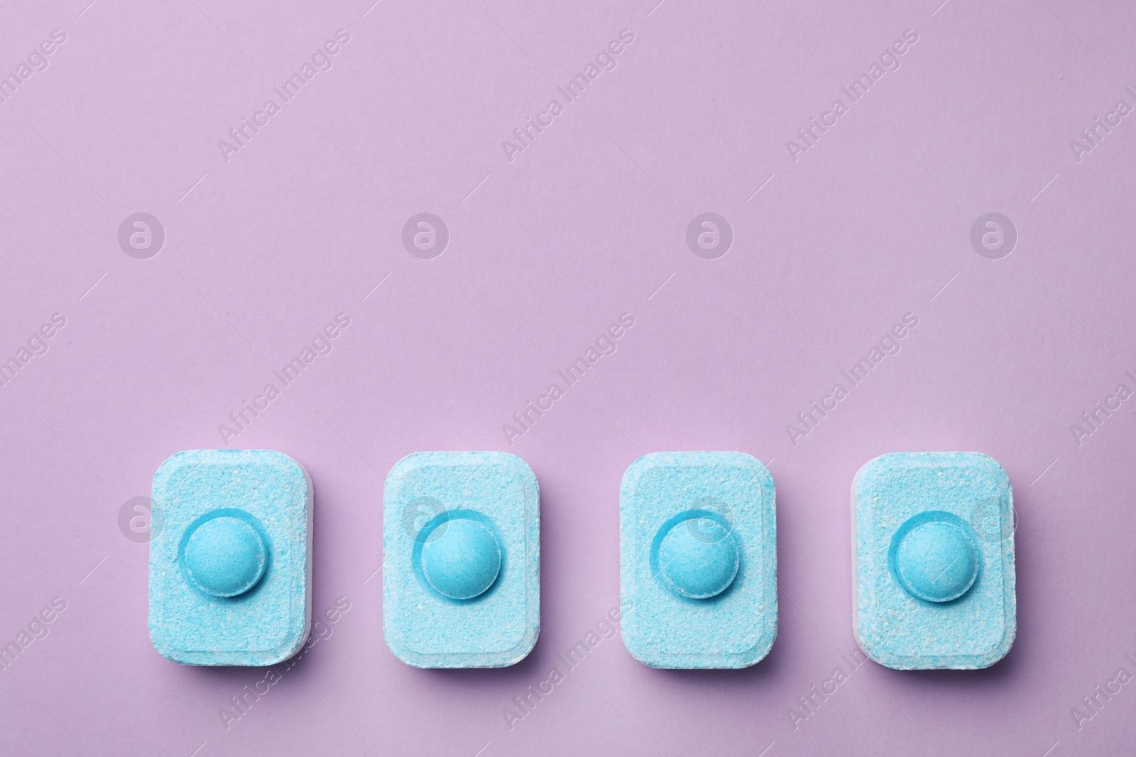 Photo of Water softener tablets on violet background, flat lay. Space for text