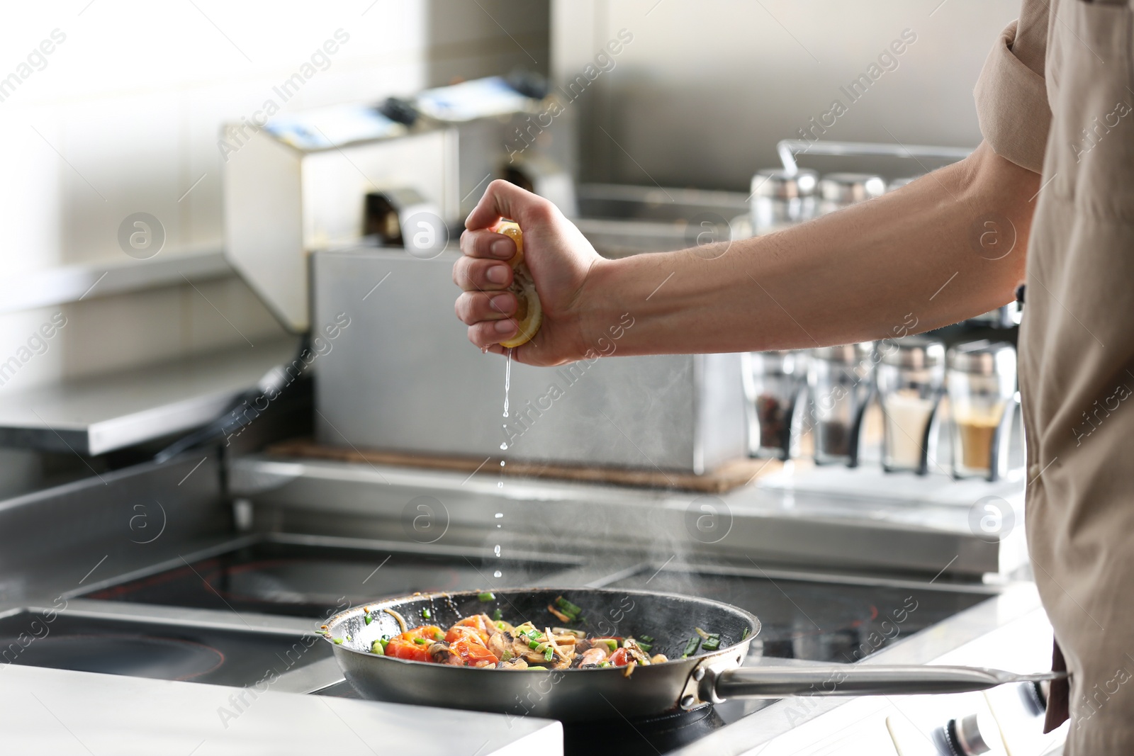Photo of Male chef cooking tasty food on stove in restaurant 
kitchen, closeup of hand