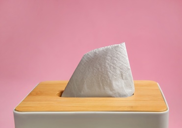 Photo of Holder with paper tissues on pink background, closeup