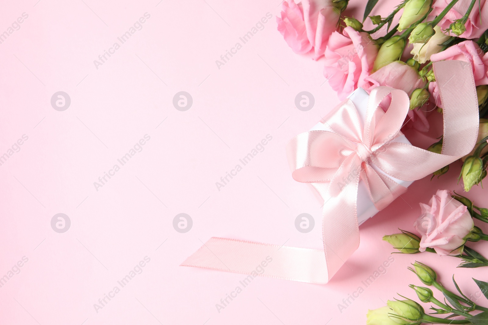 Photo of Happy Mother's Day. Beautiful flowers and gift box on pink background, flat lay. Space for text