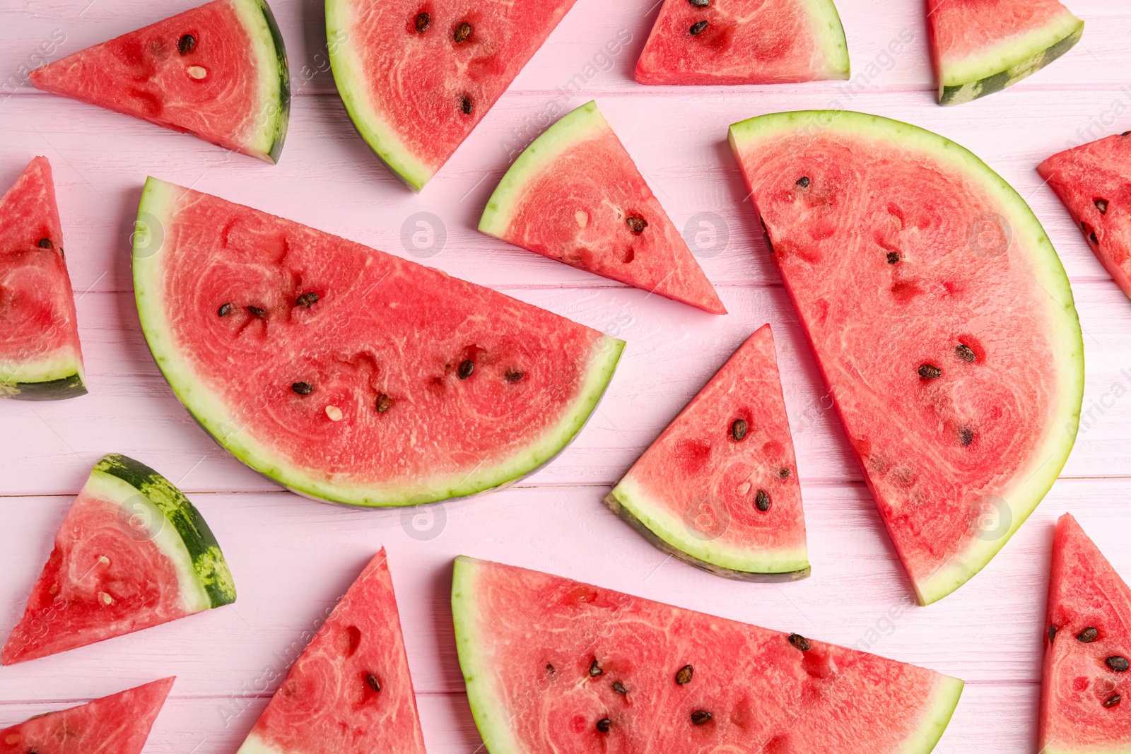 Photo of Slices of ripe watermelon on pink wooden table, flat lay