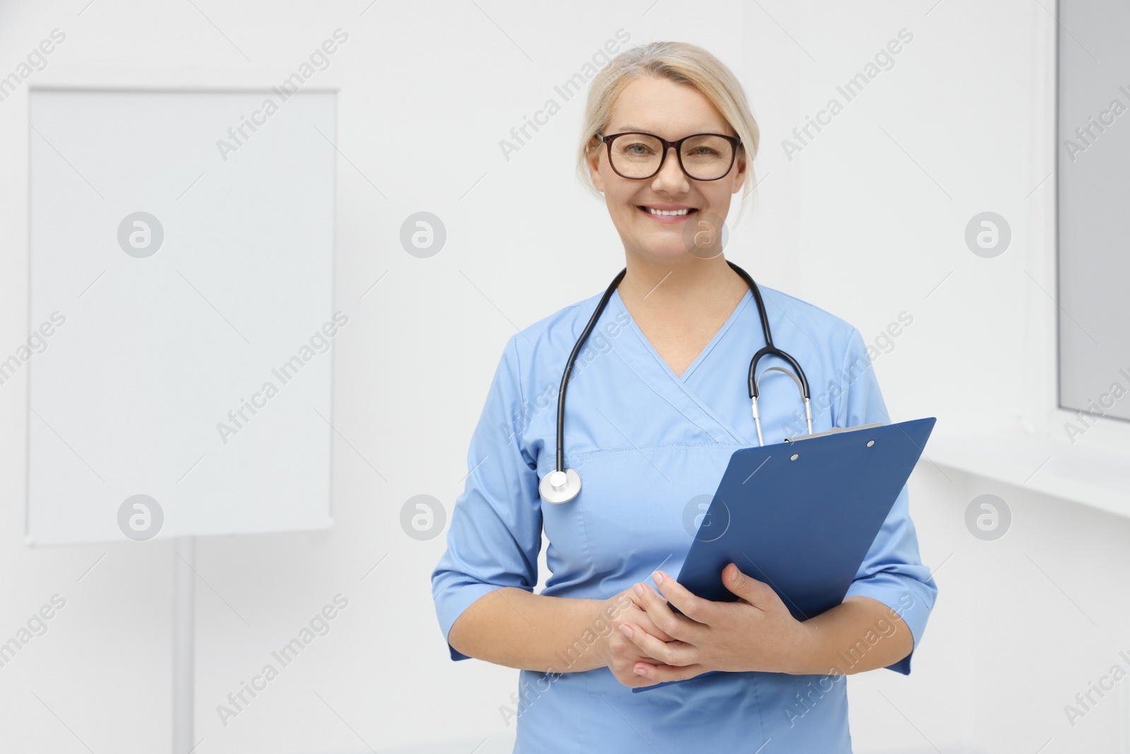 Photo of Professional doctor wearing uniform near flipchart in clinic