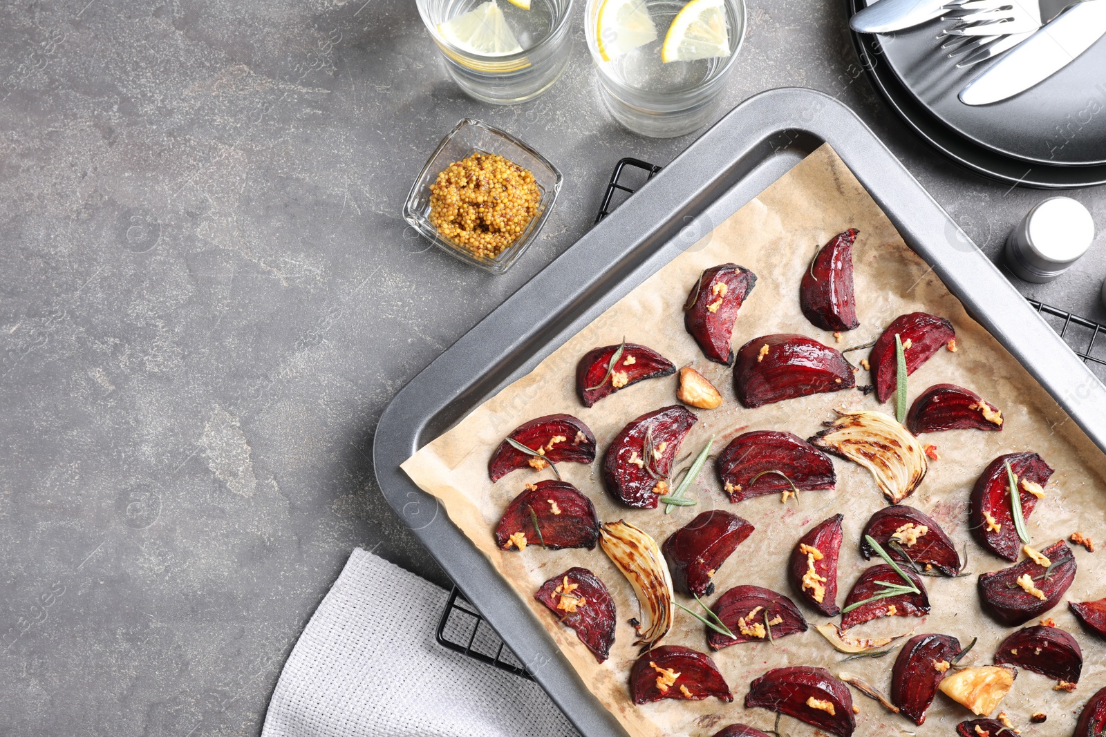 Photo of Baking tray with roasted beetroot slices on grey table, flat lay