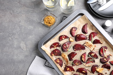 Photo of Baking tray with roasted beetroot slices on grey table, flat lay