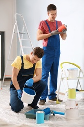 Male decorators working with paint indoors