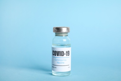 Photo of Vial with coronavirus vaccine on light blue background