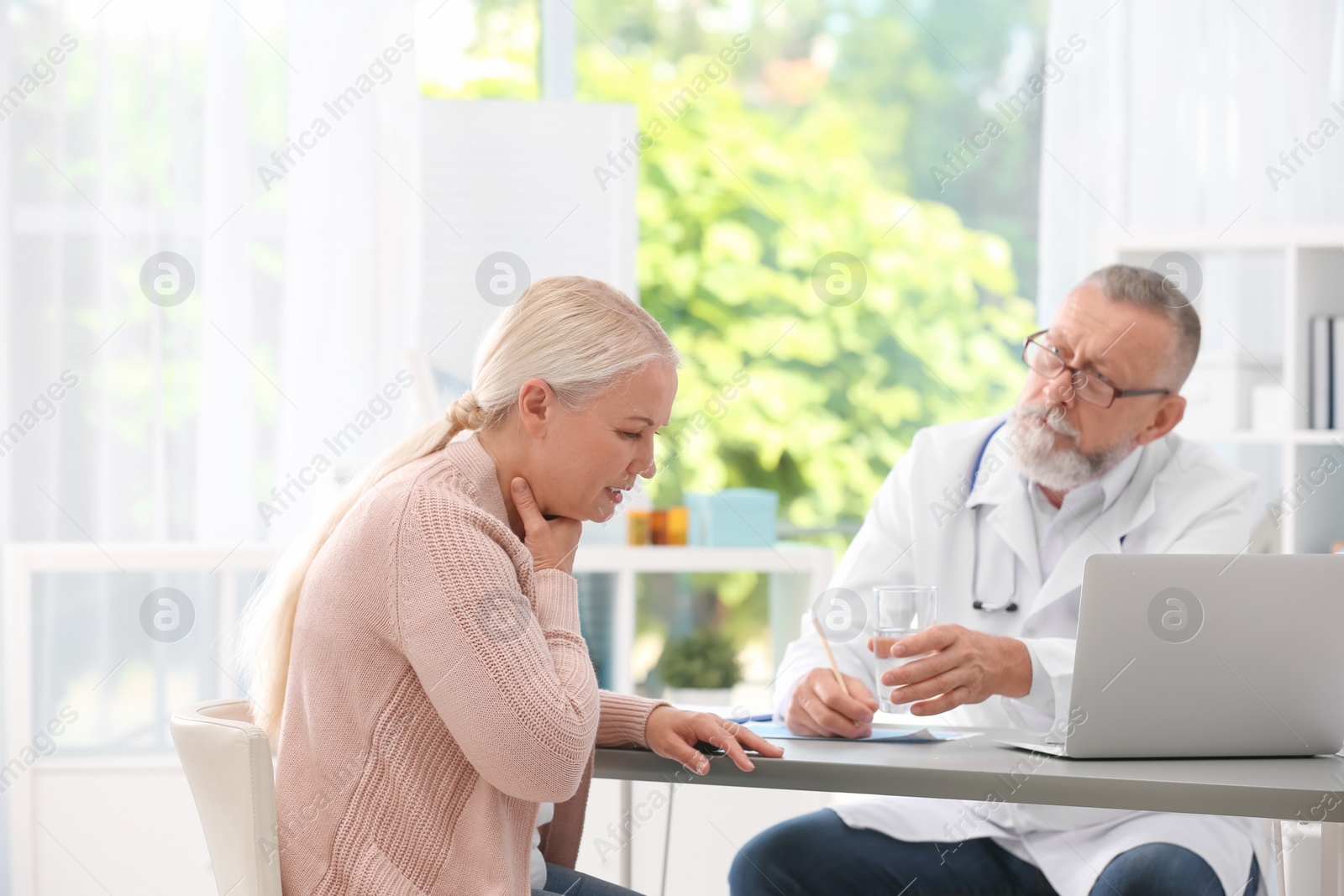 Photo of Coughing mature woman visiting doctor at clinic