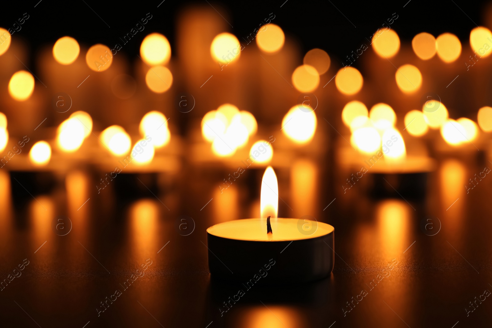 Photo of Burning candle on black table. Memory day