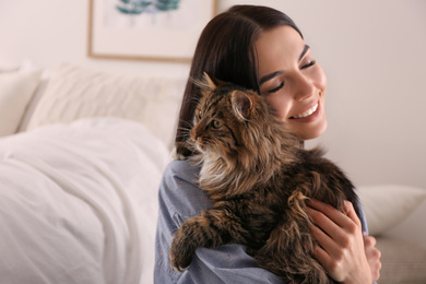 Beautiful young woman with her cute cat in bedroom. Fluffy pet