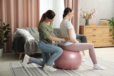 Photo of Doula massaging pregnant woman at home. Preparation for child birth