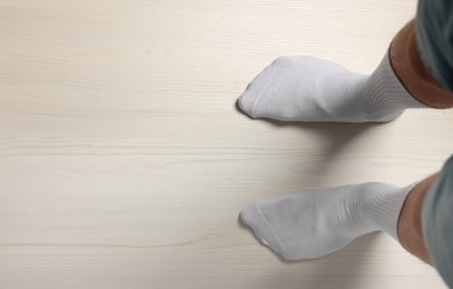 Photo of Man in stylish socks standing on white wooden floor, top view. Space for text