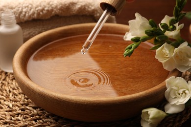 Photo of Dripping essential oil into bowl on table. Aromatherapy treatment
